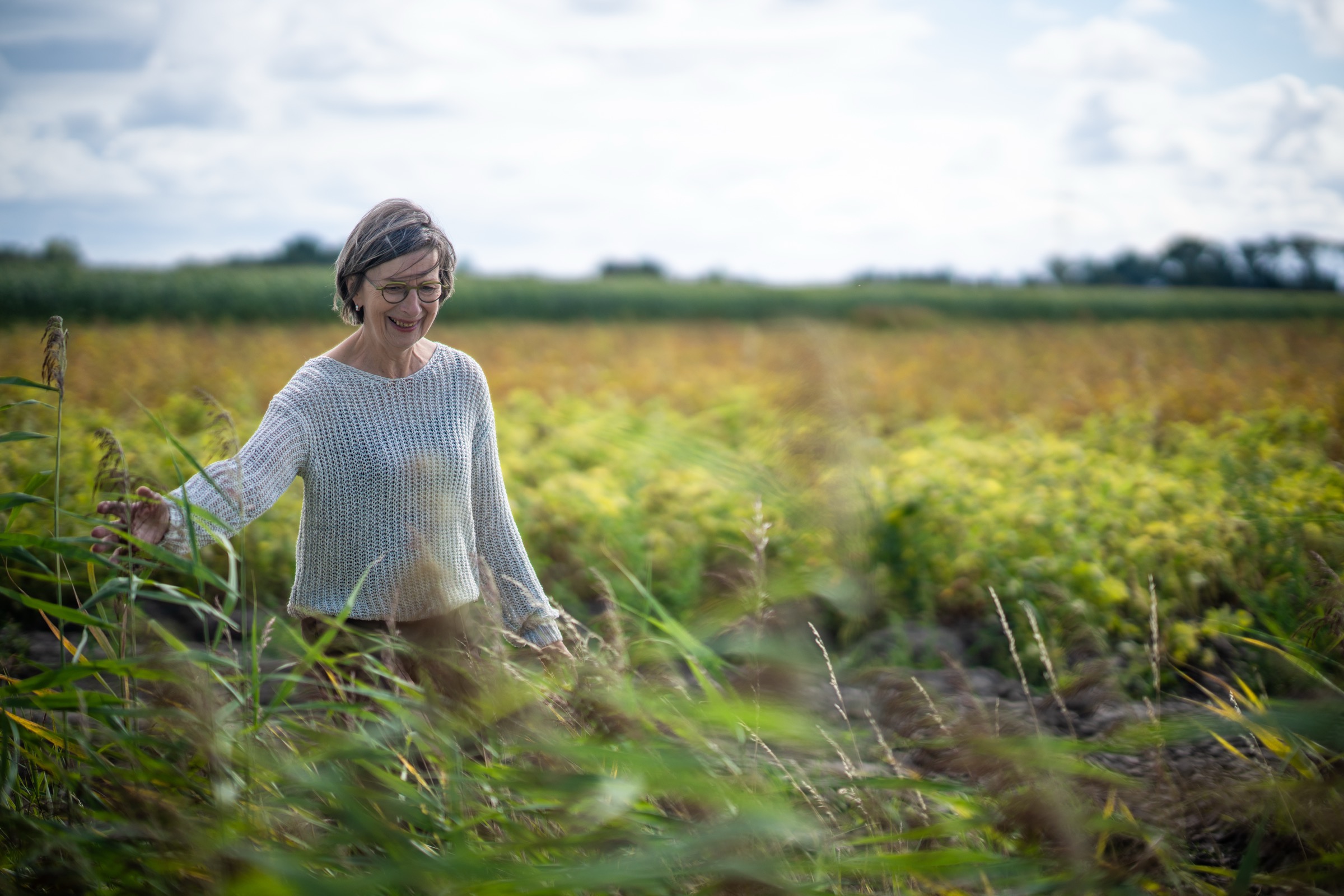 Rita van der Laag loopt door een veld met hoog gras, blik naar beneden