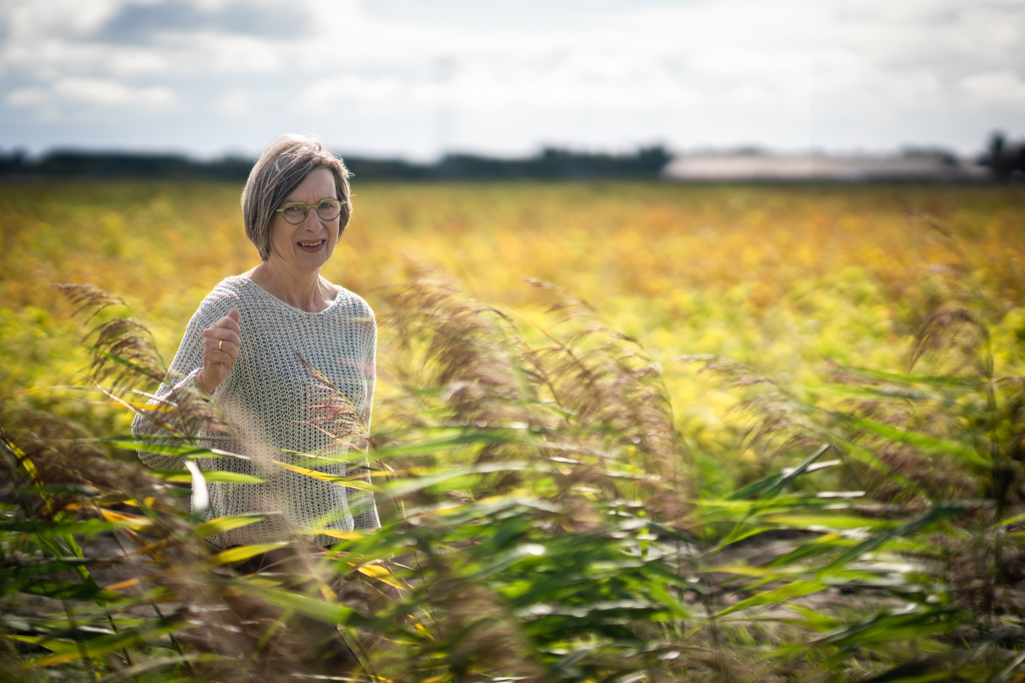 Rita van der Laag staat lachend tussen het hoge riet