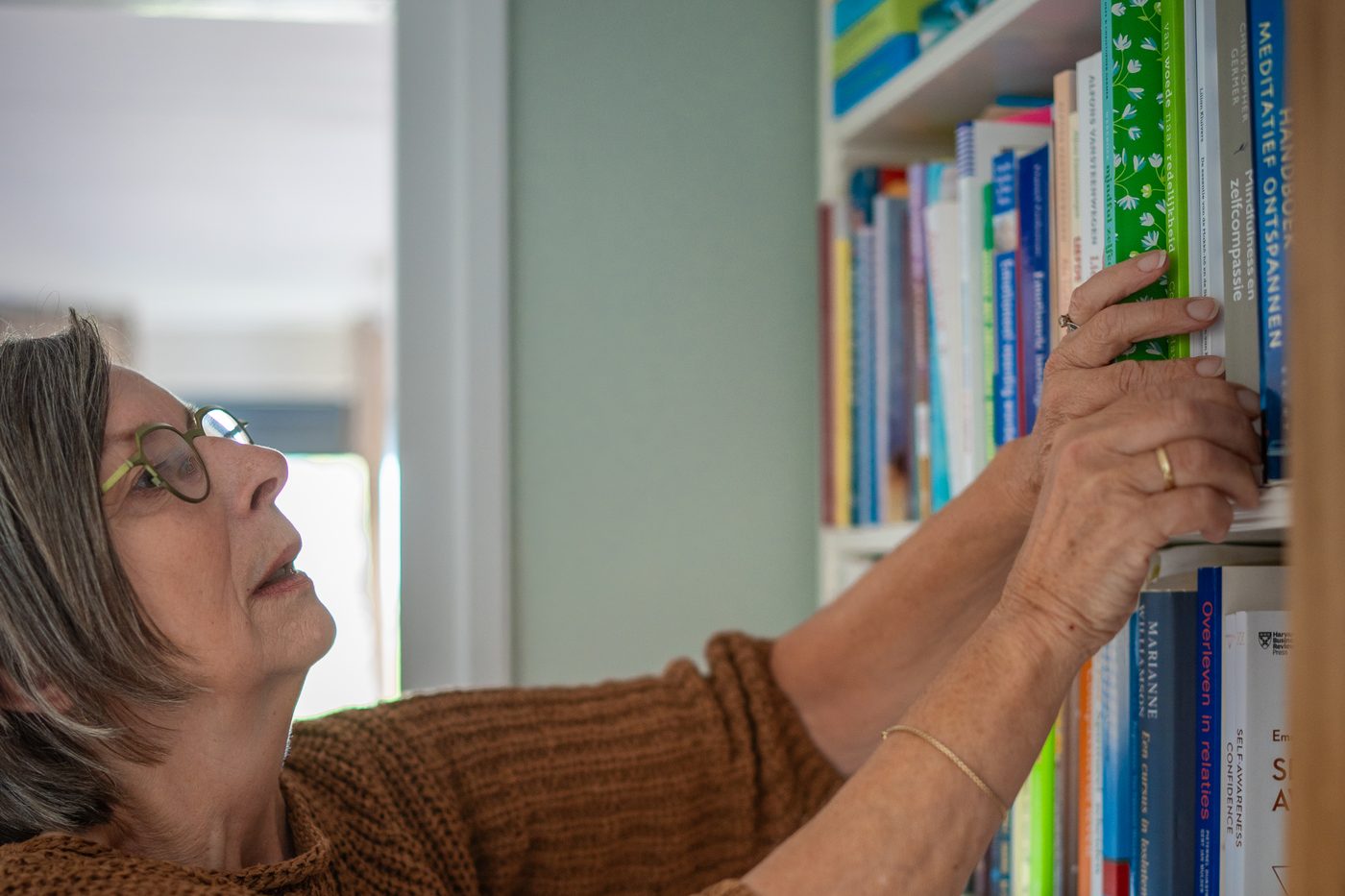 Rita van der Laag pakt een boek uit haar boekenkast
