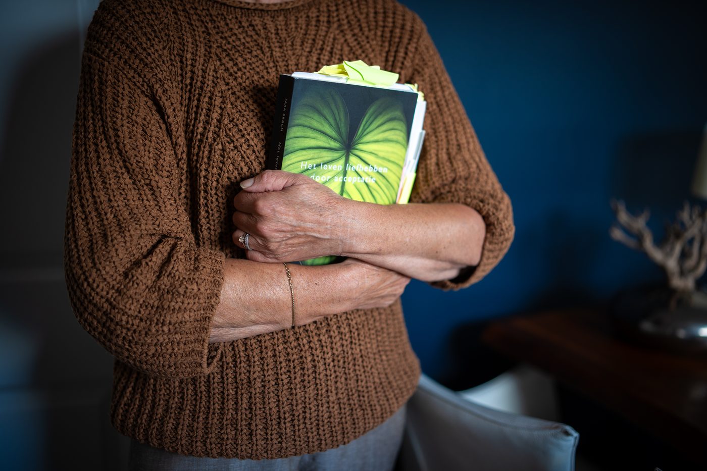 Rita van der Laag met een boek tegen zich aan in haar praktijk